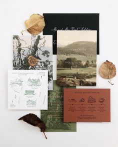 the wedding stationery is laid out on top of each other, including an autumn leaf