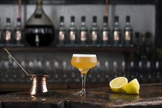 a glass of lemonade sits next to a small metal cup on a bar counter