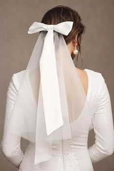 a woman wearing a veil with a white bow on it's head and back