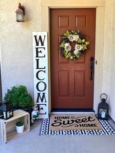 a welcome sign on the front door of a house with potted plants next to it