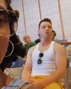 two people sitting next to each other in front of a group of people wearing sunglasses