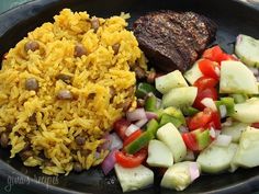 rice and vegetables in a skillet with some meat on the side, as well as other food items