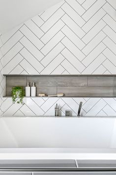 a white kitchen with herringbone tile on the wall and shelves above it, along with utensils