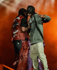 two people standing next to each other on stage with one person wearing a leather vest