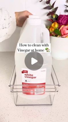 a bottle of vinegar sitting on top of a counter next to a vase with flowers