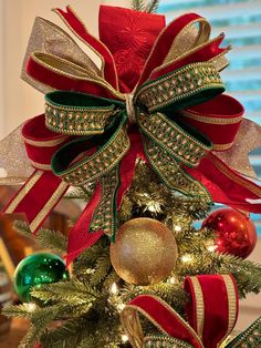 a christmas tree decorated with red, green and gold ribbon bowes on it's top