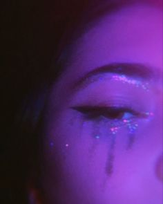 a woman's face with glitter on it and her eyeliners are purple