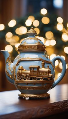 a teapot with a train on it sitting on a table in front of a christmas tree