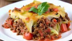 a white plate topped with lasagna covered in meat and vegetables