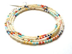 Ivory glass seed beads with stripes and 14k gold filled accents. The pieces can be worn as a wrap bracelet, necklace, or anklet. Measures 27". White Heishi Beads Single Strand Jewelry, White Multi-strand Summer Jewelry, White Multi-strand Jewelry For Summer, Summer Multi-strand White Jewelry, Summer White Multi-strand Jewelry, White Multi-strand Bracelets With Colorful Beads, White Multi-strand Beaded Bracelets For Beach, White Multi-strand Beaded Bracelets With Spacer Beads, White Multi-strand Hand-strung Jewelry