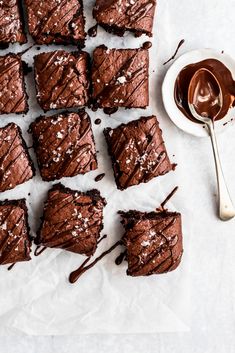 chocolate brownies cut into squares and sitting on a piece of parchment paper next to a jar of honey