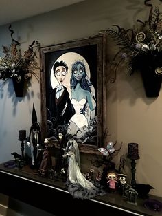 a man and woman are standing in front of a painting on the wall next to candles