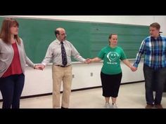 three people holding hands in front of a blackboard