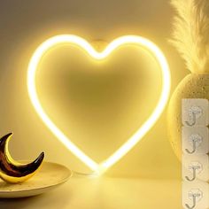 a heart shaped neon sign next to a banana on a plate with a feather in it