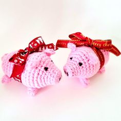 two pink crocheted pigs with red bows