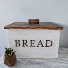 a wooden box with the word bread on it next to a small potted plant