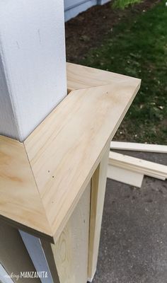 an unfinished piece of wood sitting on top of a wooden table next to a building