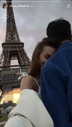 a man and woman standing in front of the eiffel tower