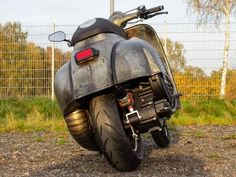 a motorcycle parked on the side of a dirt road next to a fenced in area