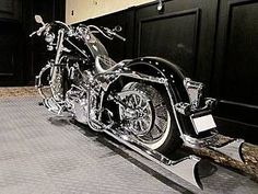 two motorcycles parked next to each other on the ground in front of a building with black doors