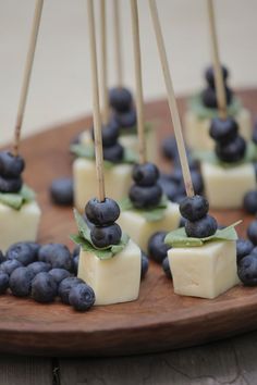 blueberries and cheese are arranged on skewers