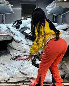 a woman standing next to a pile of plastic bags in a room filled with trash