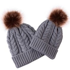 two gray knitted hats with brown pom - poms on top of each other