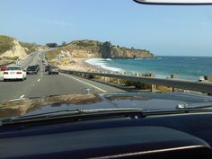 cars driving down the road next to the ocean