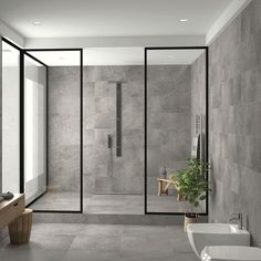 a modern bathroom with grey tiles and white fixtures, along with a plant in the corner