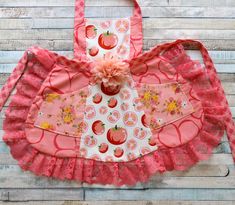 a pink apron with an apple design on the front, and a flower in the center