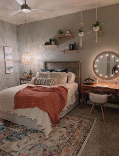 a bed room with a neatly made bed next to a desk and mirror on the wall