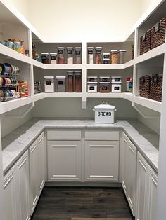 a kitchen with white cabinets and shelves filled with food