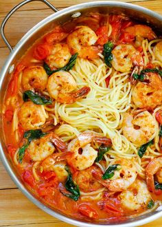 a pan filled with pasta and shrimp on top of a wooden table