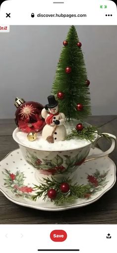 a teacup with christmas decorations on it and a small tree in the middle is shown