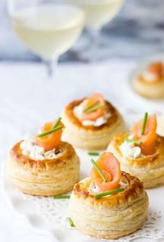 small appetizers are arranged on a plate with wine glasses in the back ground