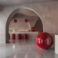 a large red ball sitting in the middle of a room next to a counter with bottles on it