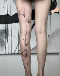 a woman's legs with tattoos on them and flowers growing out of the leg