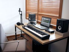 an electronic keyboard sitting on top of a wooden desk next to a monitor and speakers