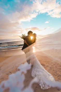 a bride and groom kissing on the beach