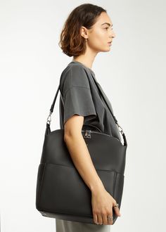 a woman carrying a black leather tote bag