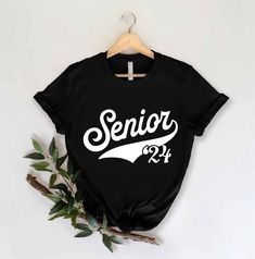 a black shirt with the word senior printed on it and a t - shirt hanging from a