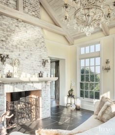 a living room filled with furniture and a fire place under a chandelier above a fireplace