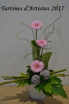 a vase with pink flowers and greenery on a table next to a sign that says tartins d'artistes 2017