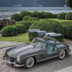 an old mercedes sports car is parked by the water