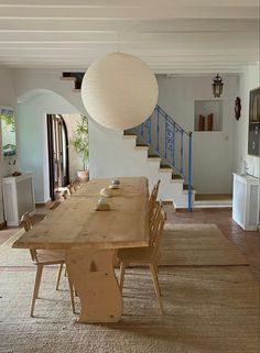 a dining room table with chairs and a light fixture hanging from it's ceiling