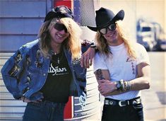 two young men standing next to each other in front of a tall metal structure wearing cowboy hats