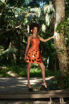 a woman in an orange dress standing next to a tree