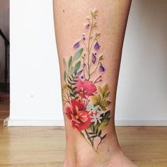 a woman's foot with flowers and leaves on the bottom part of her leg