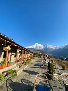 several chairs and tables are lined up on the side of a road with mountains in the background