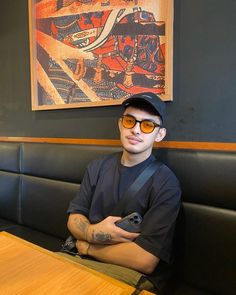 a man sitting at a table with his arms crossed, wearing sunglasses and holding a remote control